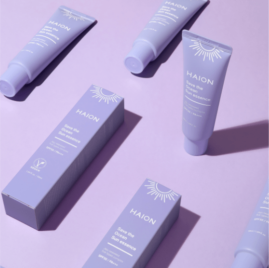 Varios tubos y cajas del protector solar de HAION en una composición sobre fondo morado, representando la línea de productos de la marca.